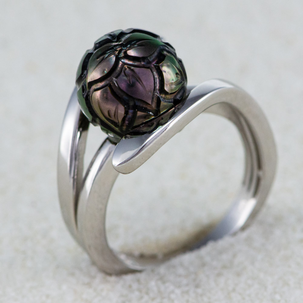 Exkluzivní prsten s vyřezávanou tahitskou perlou nejvyšší kvality. Překrásná perla je vsazena do stříbrného komponentu zhotoveného z polárního rhodia. Vysoká váha stříbra. Můžete najít online i v našem největším showroomu v Praze.